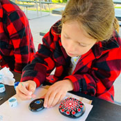 student painting designs on rocks