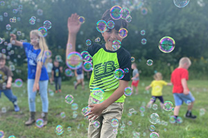 Students playing with bubbles on the grass