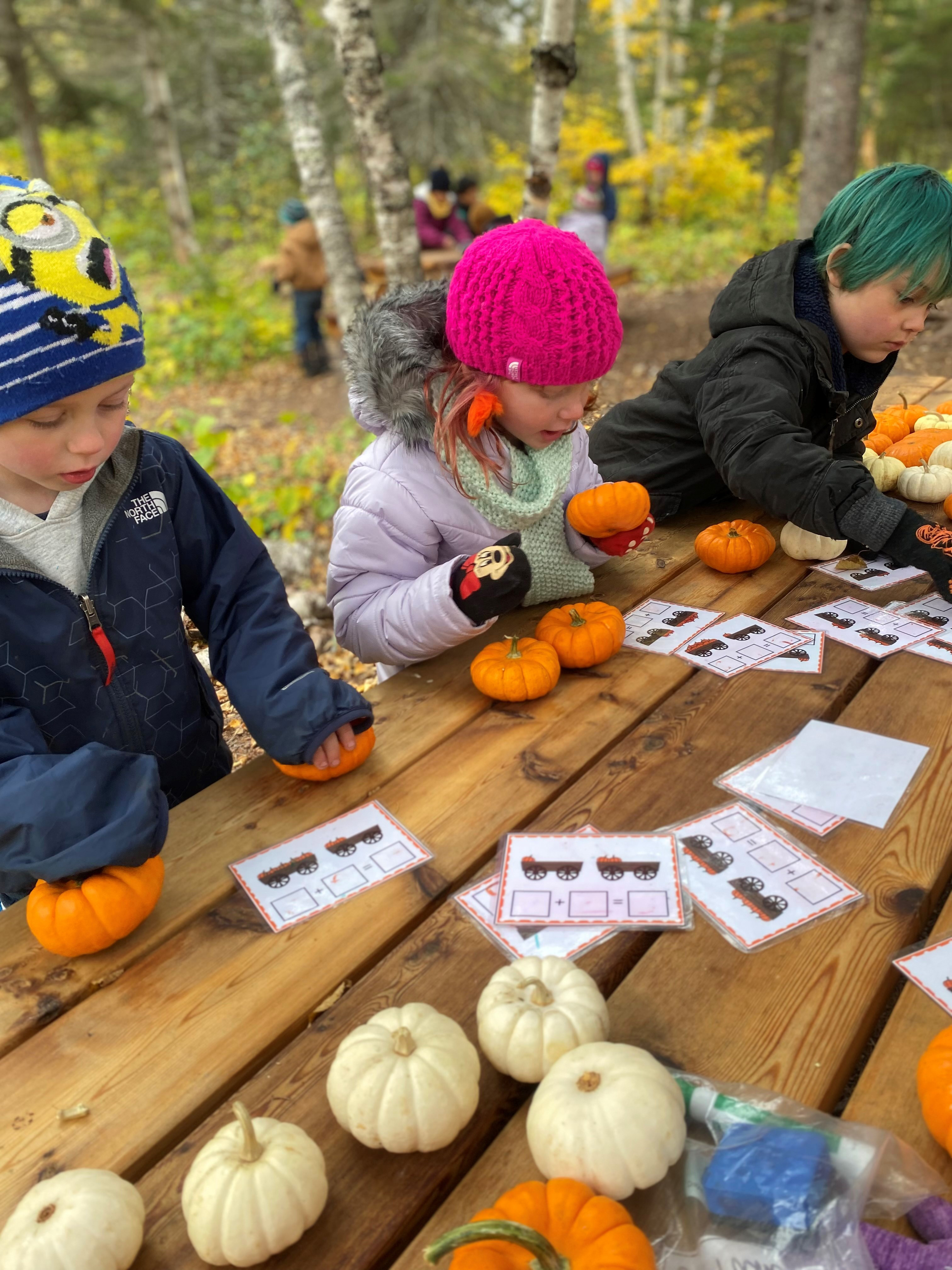 Students working with pumpkins at outdoor table