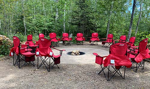 Red camp chairs around a fire