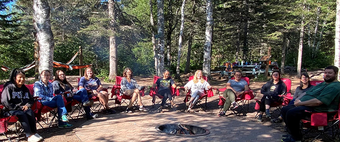 Birch Grove staff sitting in camp chairs out in the woods