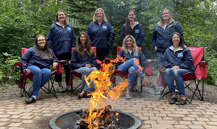 Birch Grove staff sitting in camp chairs out in the woods