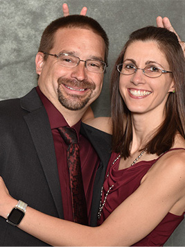 Man and woman holding fingers up behind each other's heads