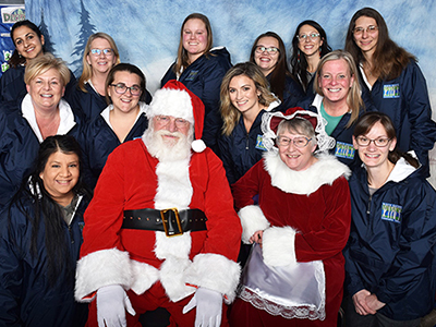 Staff members sitting with Santa and Mrs. Claus