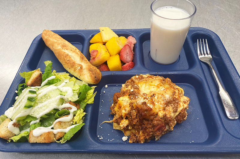 Lasagna, salad, fruit salad, bread, and glass of milk