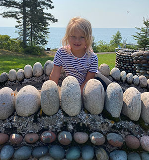 Girl sitting on rock bridge by Lake Superior