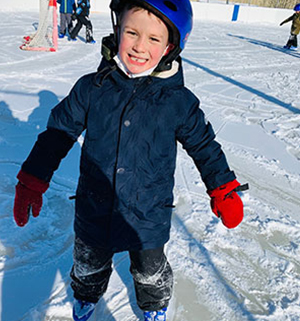 Boy ice skating and wearing a helmet for hockey
