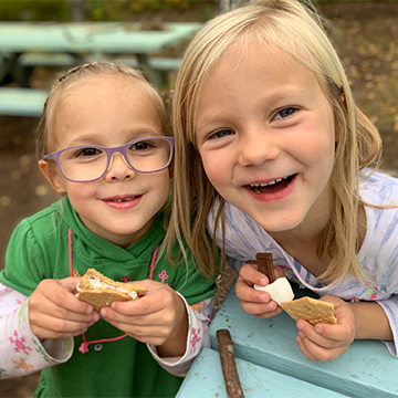 Two female students smiling with smores in their hands