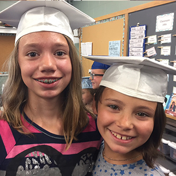 Two happy girls wearing graduation hats