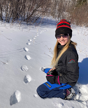 girls outside in the snow next to animal tracks