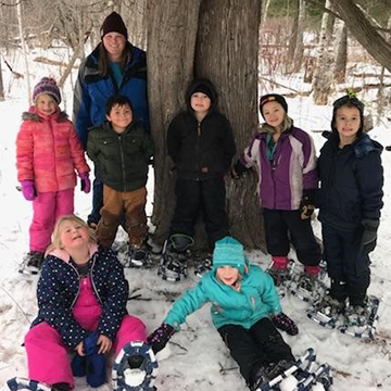Group of students with teacher posing in the snow out in the woods
