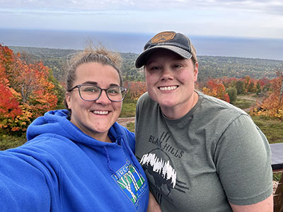 Two ladies smiling overlooking the autumn forest